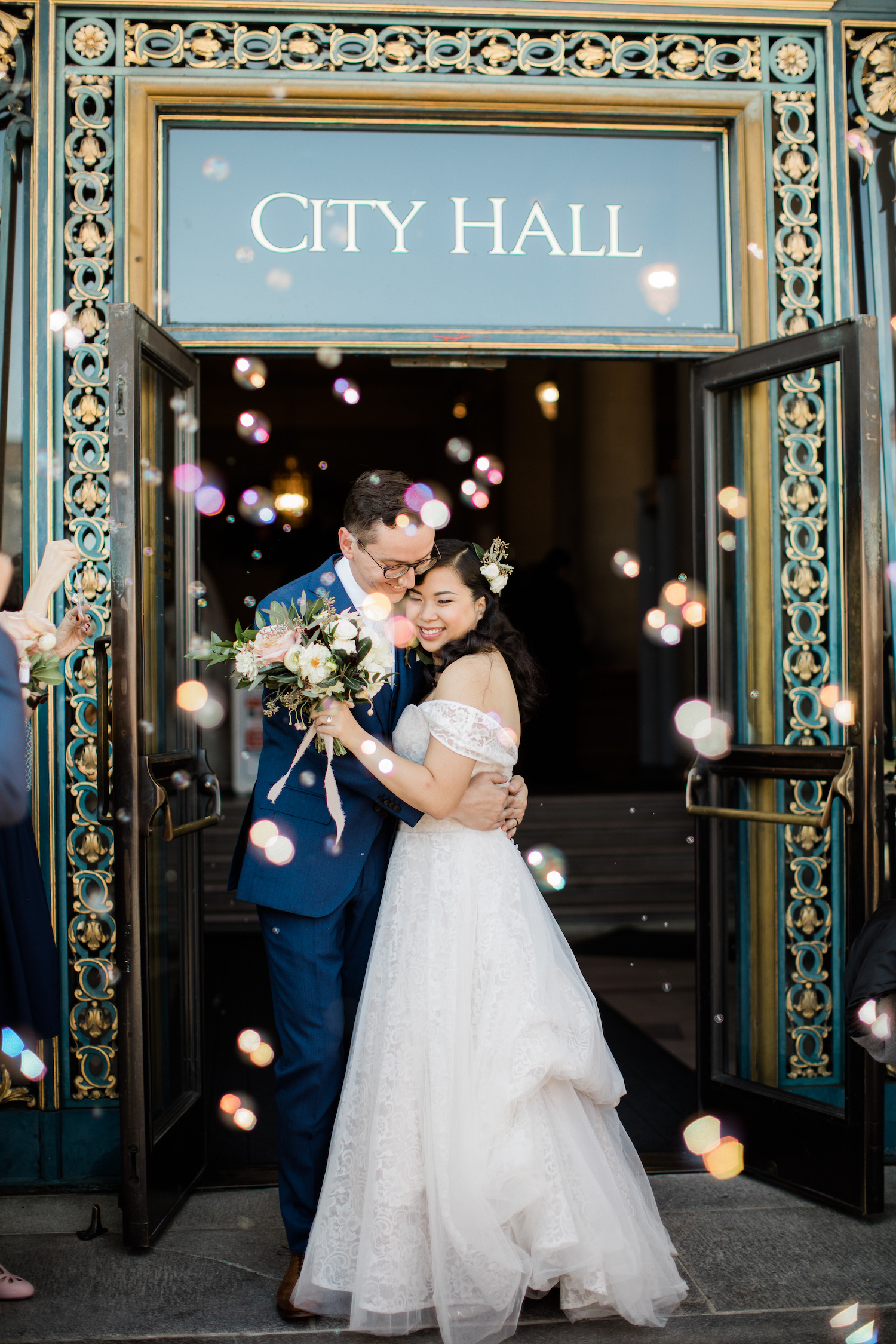 A wedding couple embrace at the door way to City Hall.