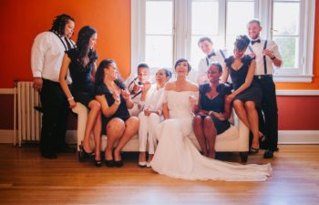 A wedding party sit and laugh, piled onto a couch.