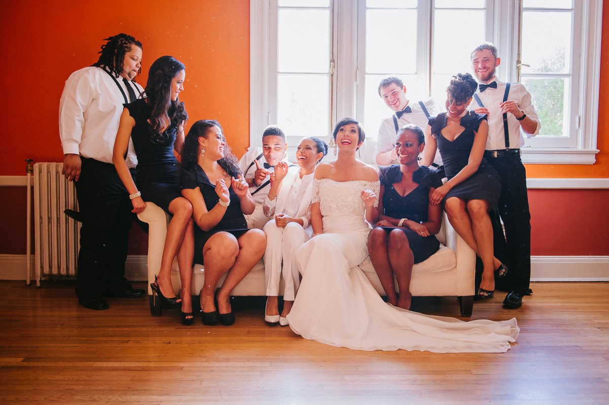 A wedding party sit and laugh, piled onto a couch.