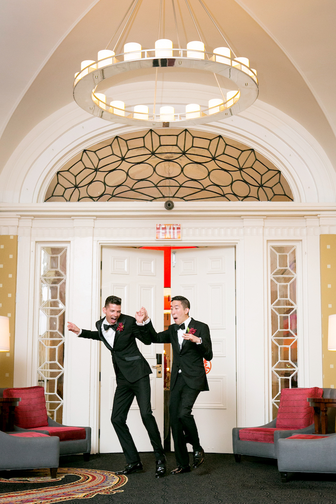 A wedding couple hold hands and smile as they enter their reception.