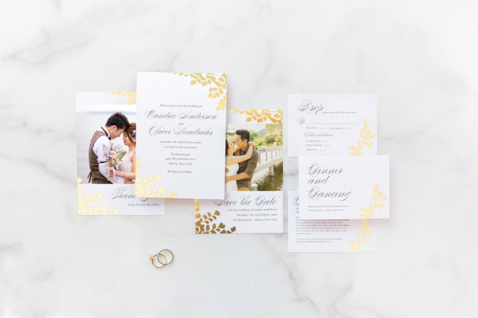 Flat lay of the complete Foliage Wedding Suite from the Martha Stewart for Mixbook Collection featuring rings, an invitation, rsvp card, thank you card and more.