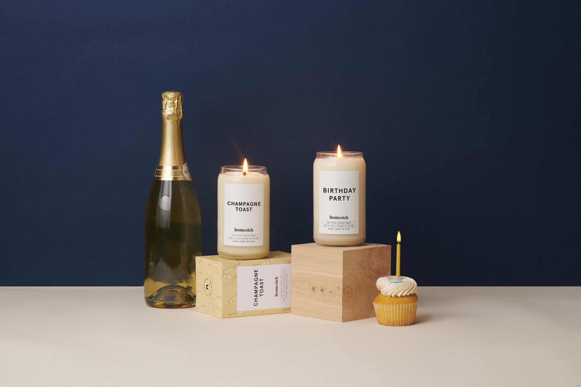 a bottle of champagne with two candles and a cupcake