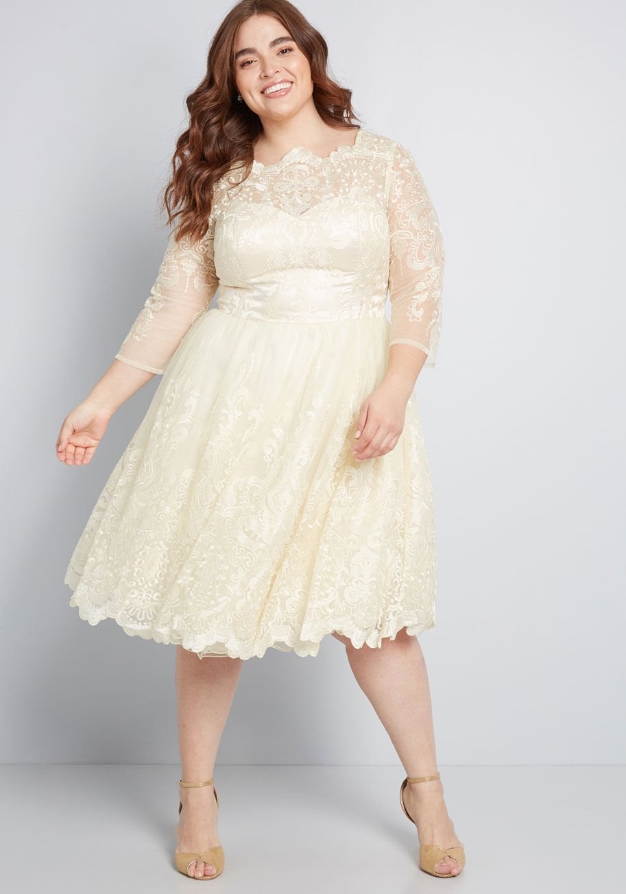Woman with dark hair in short cream lace wedding dress