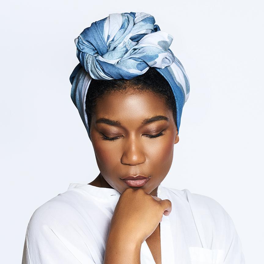 black woman wearing a headwrap with her chin on her hand and her eyes closed