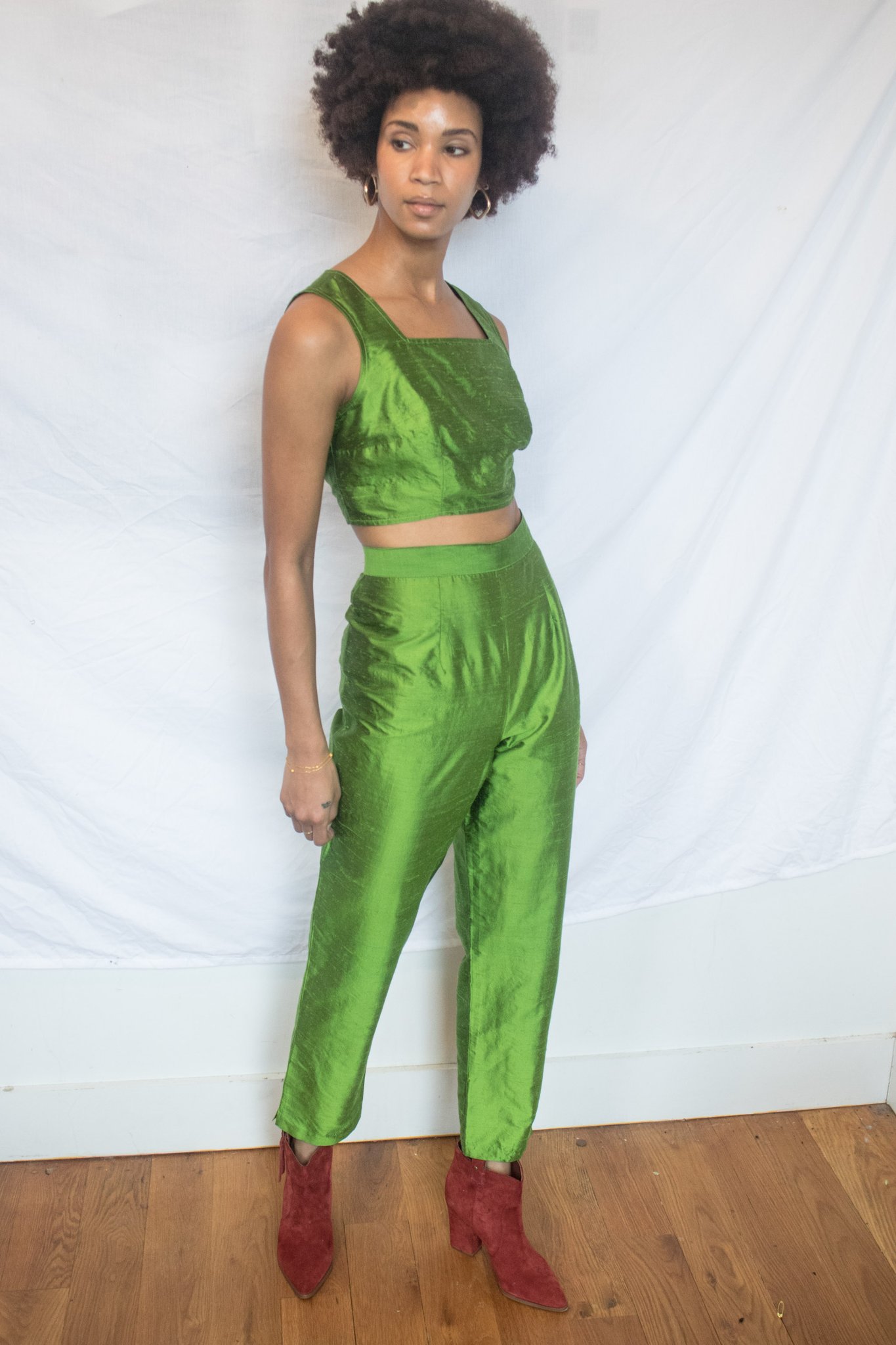 black woman with natural hair wearing a green crop top and matching pants with orange boots