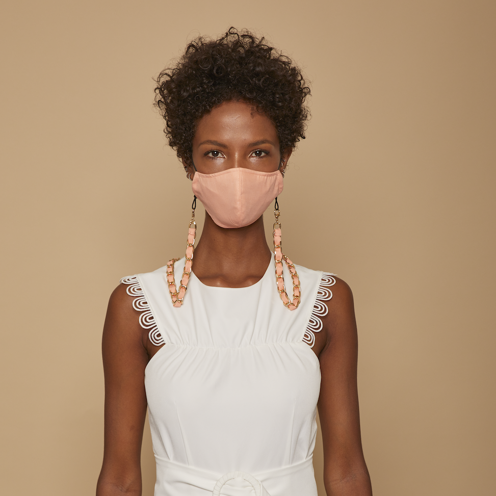 a woman wearing a white dress and peach cotton face mask with matching mask chain