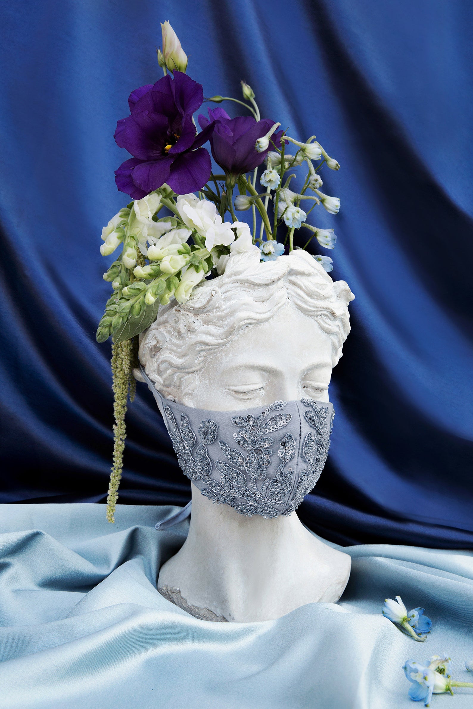 a bust vase wearing a blue embroidered mask