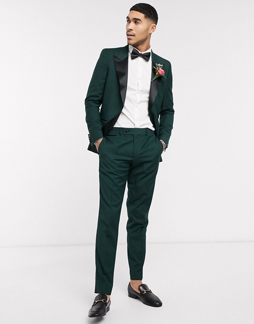 man with his hands in his pockets wearing a forest green slim fit tuxedo