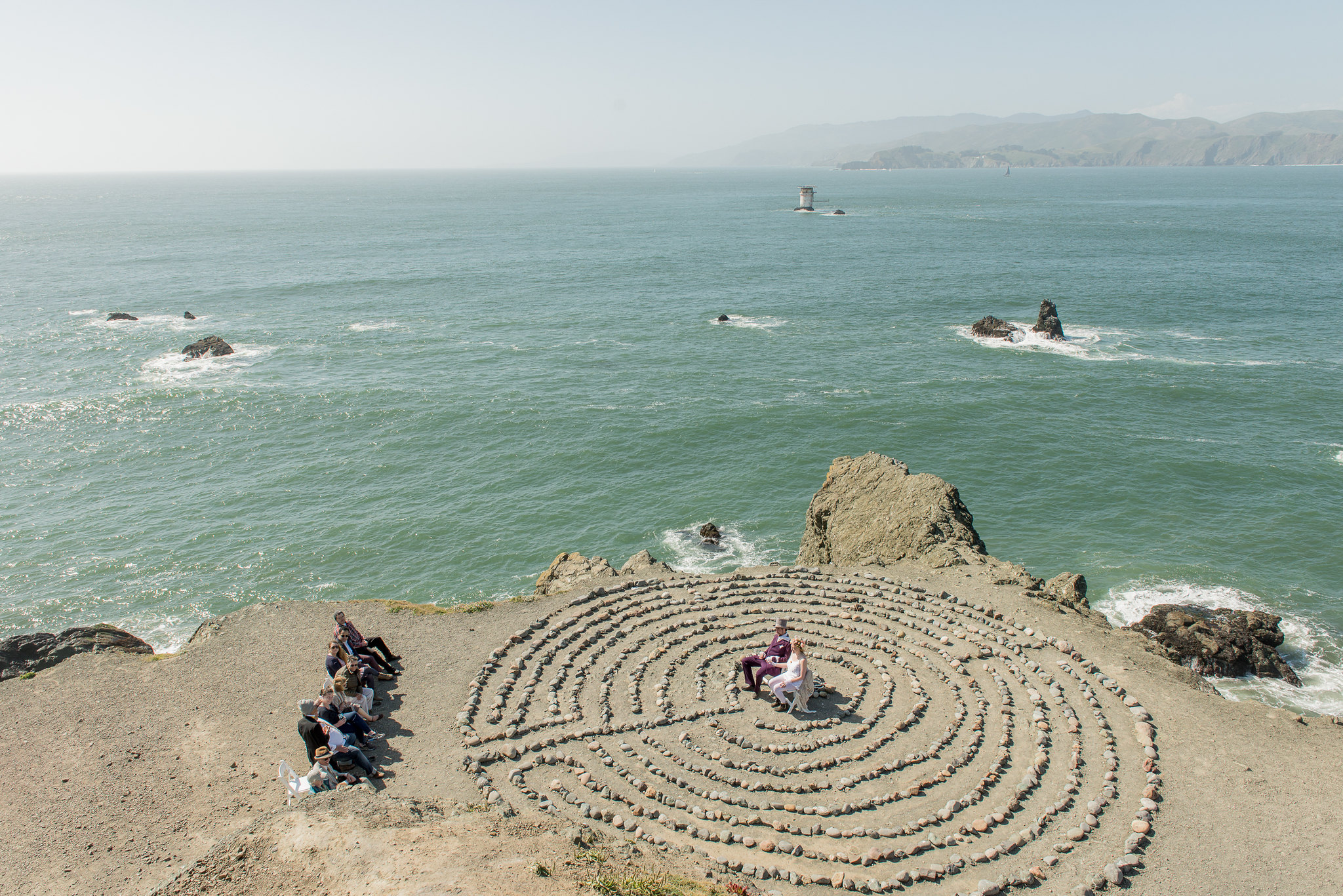 micro wedding ceremony happening in front of the ocean in a rock labrynth