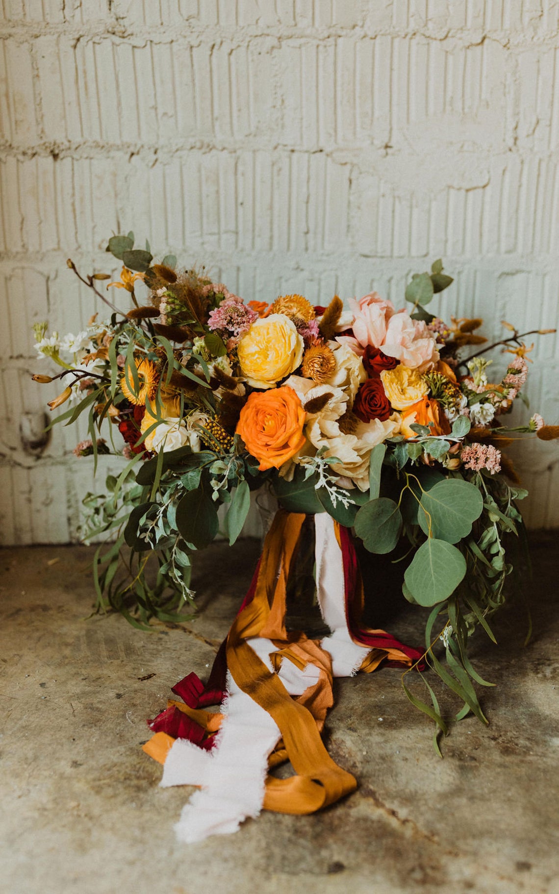 fall wedding bouquet with multiple strands of ribbon hanging from it
