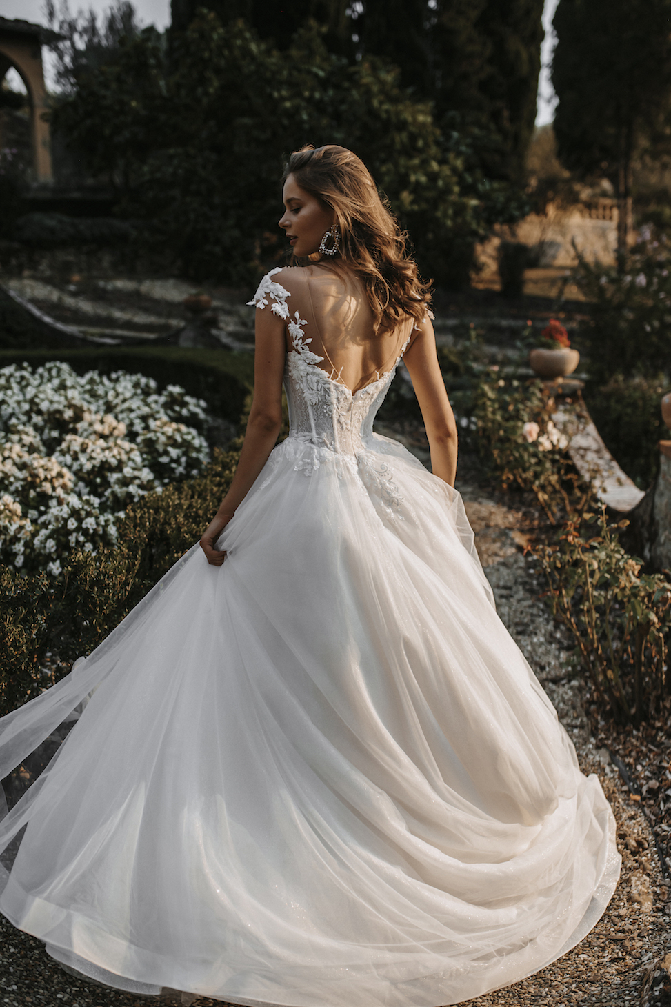 Woman twirling in a garden in a white ballgown style wedding dress
