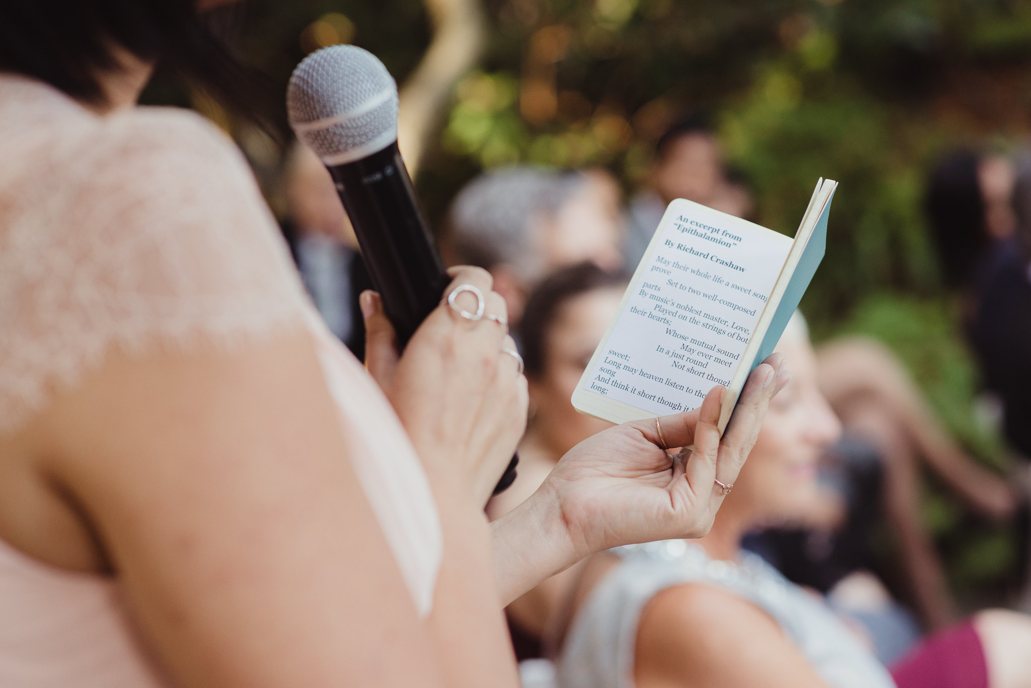 Woman holding microphone and small booklet giving maid of honor speech