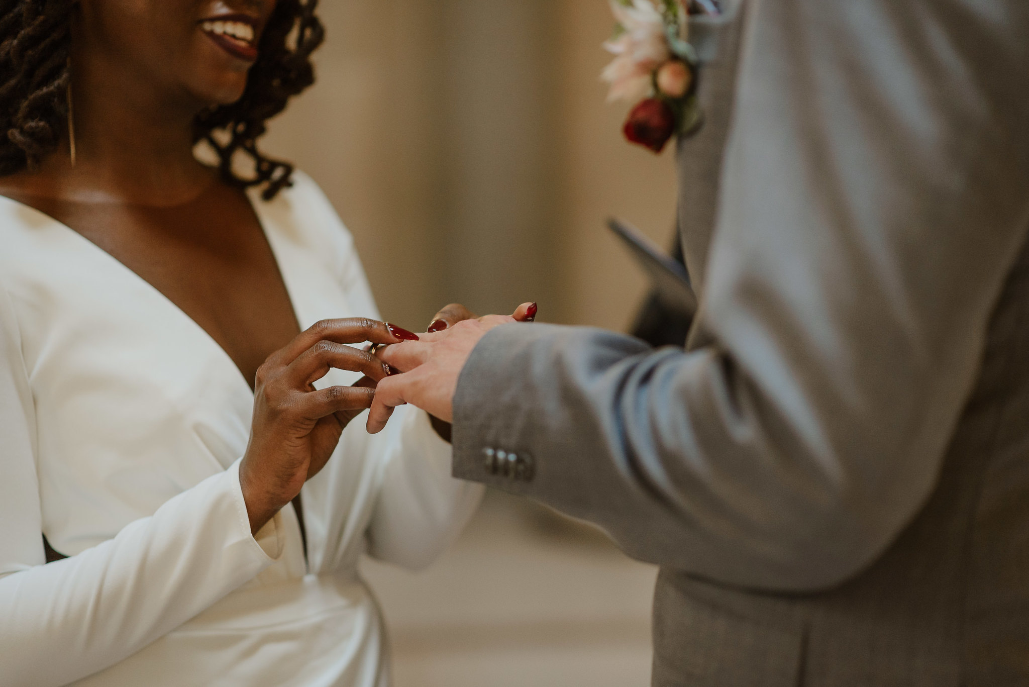 Woman in white dress placing ring on partner's finger during wedding ceremony